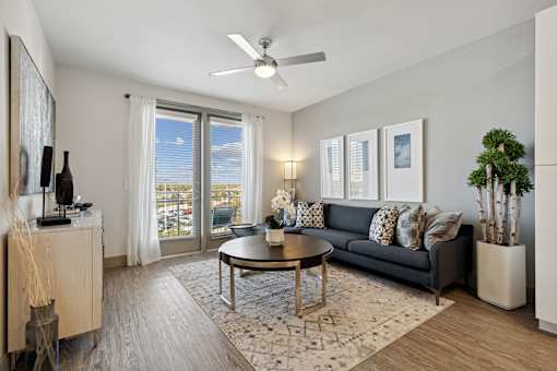 A living room with a grey couch, a coffee table, and a ceiling fan
