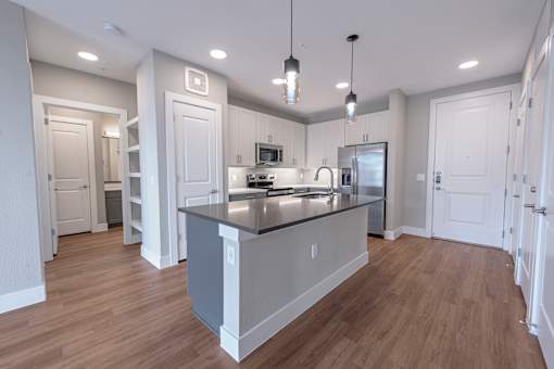 A modern kitchen with a large island and pendant lights.
