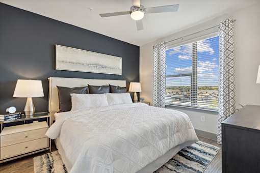 Spacious apartment bedroom with dark accent wall and floor-to-ceiling windows