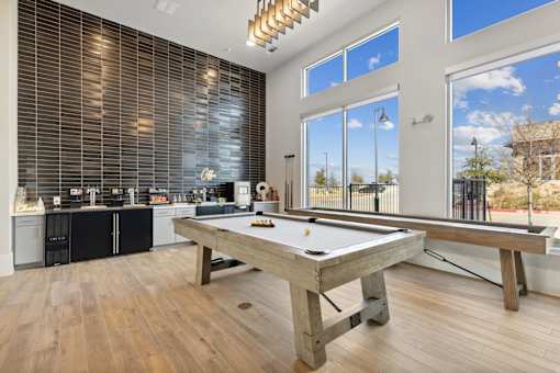A pool table in a room with a kitchen in the background