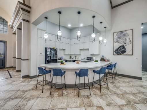 A kitchen with a bar and chairs.