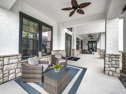 A patio with a table and chairs and a ceiling fan.