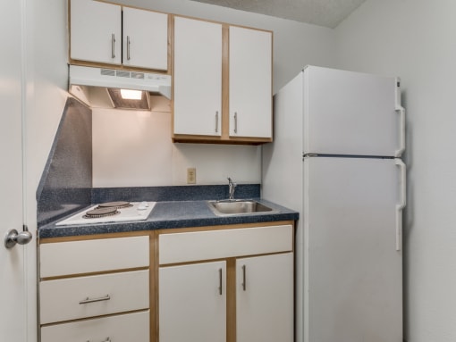 a kitchen with white cabinets and a sink and a refrigerator  at Waterford Studios, Austin, Texas