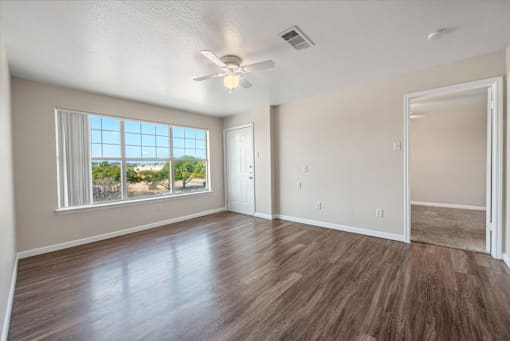 A room with a ceiling fan and a large window overlooking a landscape.