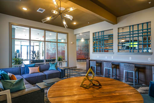 A modern living room with a round wooden table and a large window.