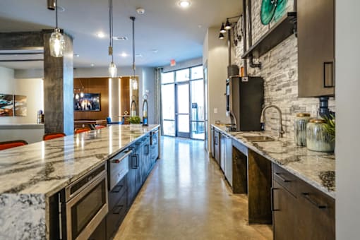 A modern kitchen with a marble countertop and dark cabinets.