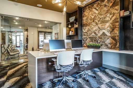 A modern office with a stone wall and two white chairs at The Grand at Manor Apartments, Manor