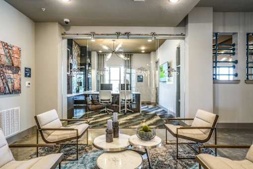 A living room with a large rug and a coffee table with a bowl of fruit on it at The Grand at Manor Apartments, Texas 78653