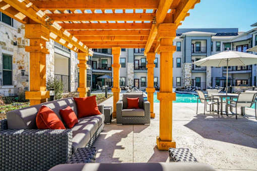 A patio with a yellow pergola and a pool table at The Grand at Manor Apartments, Manor, 78653