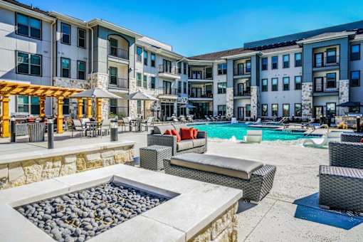 A sunny day at a resort with a pool and a hot tub at The Grand at Manor Apartments, Manor, TX