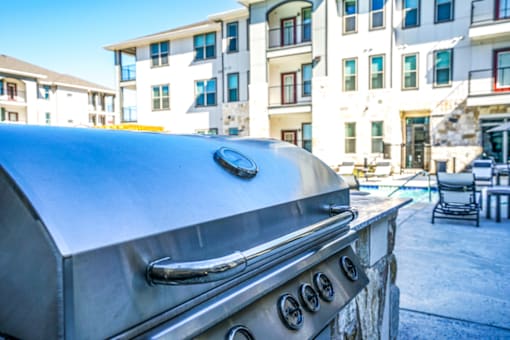 A barbeque grill and a building in the foreground, The Grand at Manor, TX
