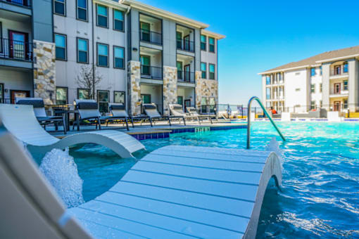 A swimming pool with a slide and a building in the background.