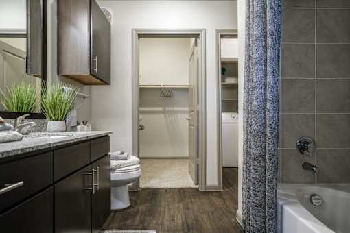 A bathroom with a toilet, sink, and bathtub at The Grand at Manor Apartments, Manor, TX