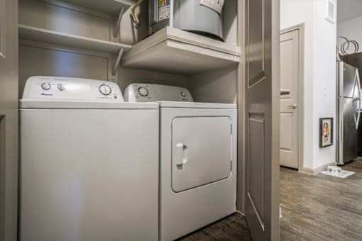 A white dishwasher is in a kitchen with a washing machine on top.
