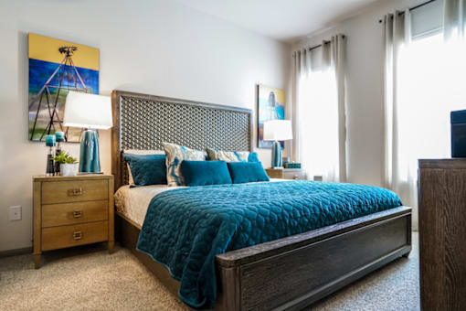 A bedroom with a bed, nightstand, and lamp.