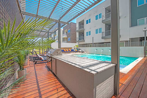 A wooden deck with a pool and a sunshade.