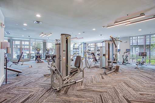 A gym with a variety of equipment including treadmills, weights, and exercise machines.