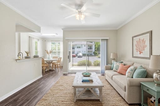 A living room with a couch, a coffee table, and a ceiling fan.