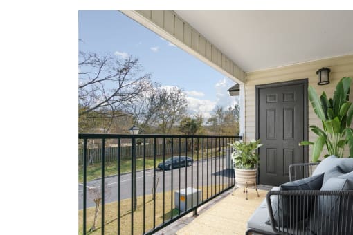 a porch with a black railing and a black door at Baldwin Farms Apartments, Robertsdale, AL, 36567