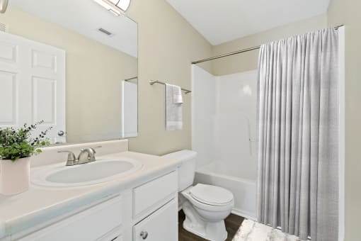 a white bathroom with a shower toilet and sink at Baldwin Farms Apartments, Robertsdale, AL