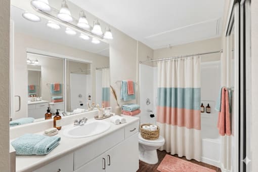 A bathroom with a white sink, toilet, and a mirror above the sink.