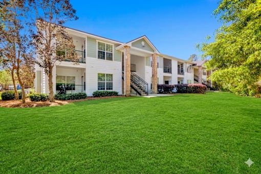 A large white building with a green lawn in front.