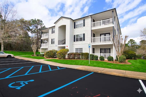 A row of white apartment buildings with green lawns in front.