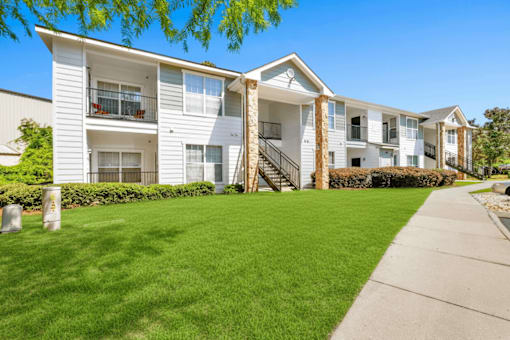 A row of white apartment buildings with green lawns in front.