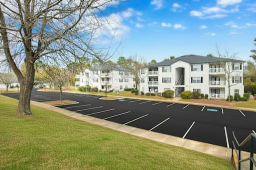 A parking lot in front of a white apartment building.
