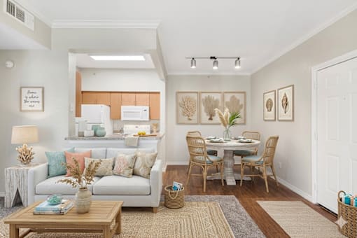 A well-lit, modern living room with a dining area and a kitchen in the background.