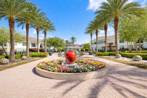 A large red sculpture is the centerpiece of a landscaped garden.