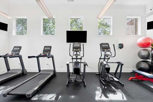A gym with treadmills, elliptical machines, and a weight bench.