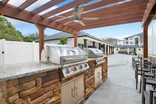 An outdoor kitchen with a grill and a fan.