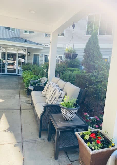 A patio with a couch, table, and potted plants.