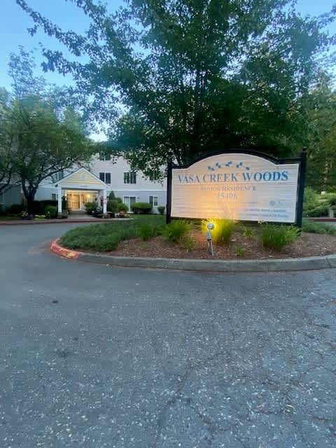 A sign for Vasa Creek Woods Seniors Residence stands in front of a building.