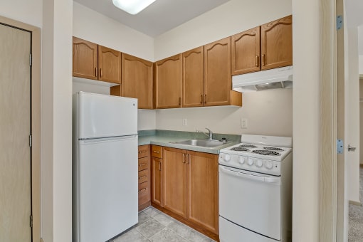 an empty kitchen with white appliances and wooden cabinets