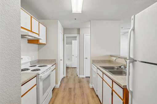 Pines at Castle Rock 2728 kitchen with white appliances and wooden cabinets.