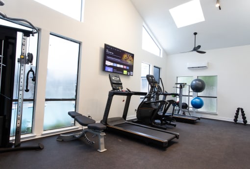 a gym with treadmills and weights and a tv