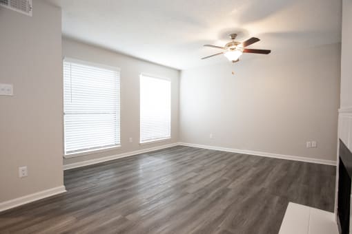 an empty living room with wood floors and a ceiling fan