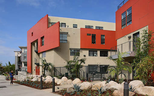 A red and beige building with a person walking in front of it.