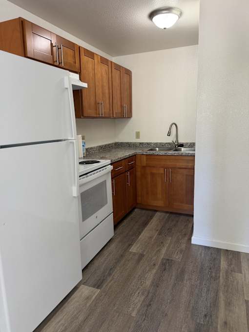 A kitchen with a white fridge and wooden cabinets.