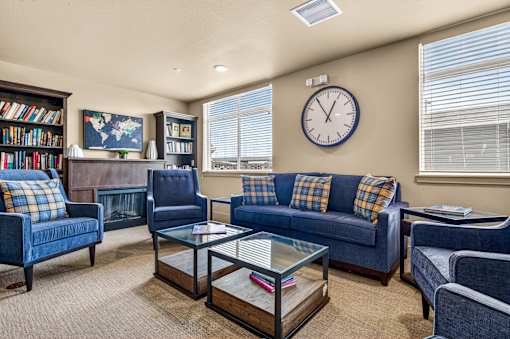 A living room with blue couches and a glass coffee table.