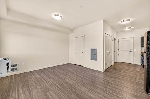 A spacious room with wooden flooring and white walls.