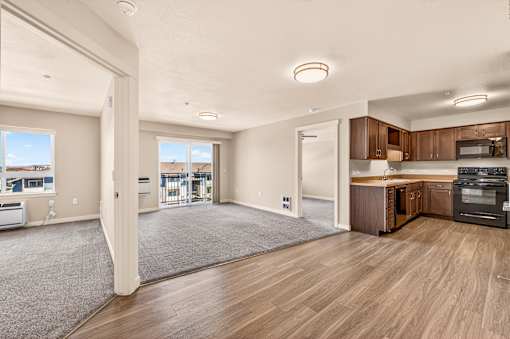 A spacious living room with a kitchen area in the background.