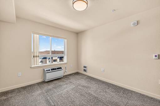 A room with a window and a wall-mounted air conditioning unit.