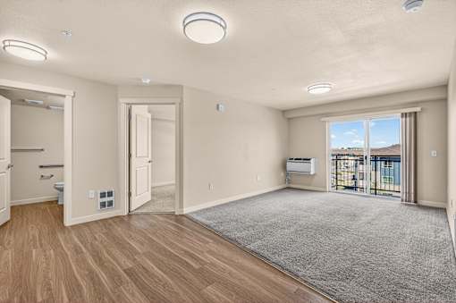 A spacious room with wooden floors and a large window.