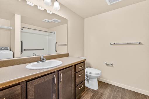 A bathroom with a sink, toilet, and a mirror.