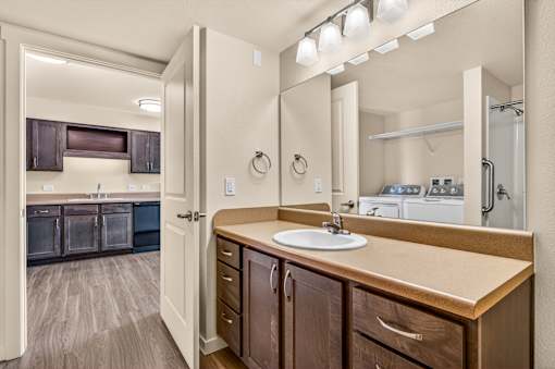 A bathroom with a sink, mirror, and wooden cabinets.