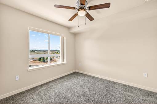 A room with a ceiling fan and a large window overlooking a landscape.