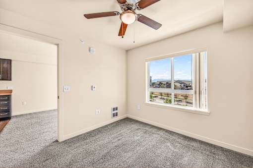 A room with a ceiling fan and a window overlooking a landscape.